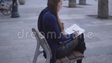 坐在城镇广场上的妇女在她的素描书上画素描